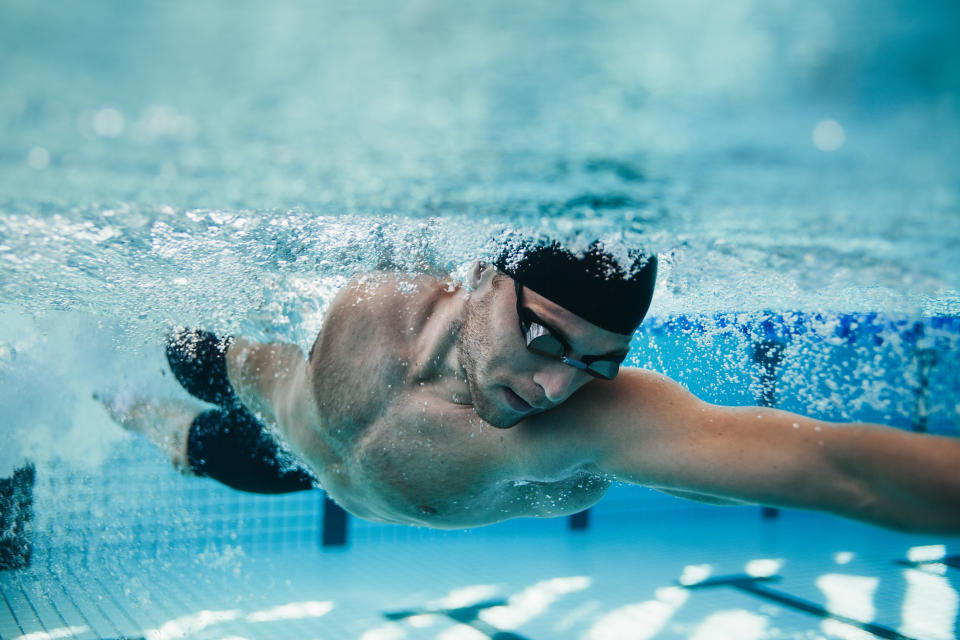 Underwater shot of fit swimmer training in the pool. Professional male swimmer inside swimming pool.