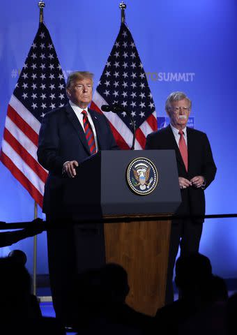 <p>Sean Gallup/Getty</p> U.S. President Donald Trump, flanked by national security adviser John Bolton, speaks to the media at a press conference on the second day of the 2018 NATO Summit