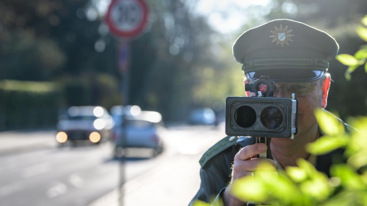 An einer Grundschule in München misst ein Polizist mit einer Laserpistole die Geschwindigkeit vorbeifahrender Fahrzeuge. Foto: Matthias Balk