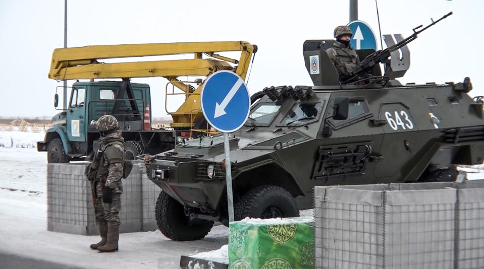 In this image taken from footage provided by the RU-RTR Russian television, A Kazakhstan's soldier stands next to a military vehicle at a check point in Kazakhstan, Friday, Jan. 7, 2022. Over 70 cargo planes are being deployed in Russia's peacekeeping mission in Kazakhstan according to the Defense Ministry chief spokesman's briefing on Friday, after the worst street protests since the country gained independence three decades ago. The demonstrations began over a near-doubling of prices for a type of vehicle fuel and quickly spread across the country, reflecting wider discontent over the rule of the same party since independence. (RU-RTR Russian Television via AP)