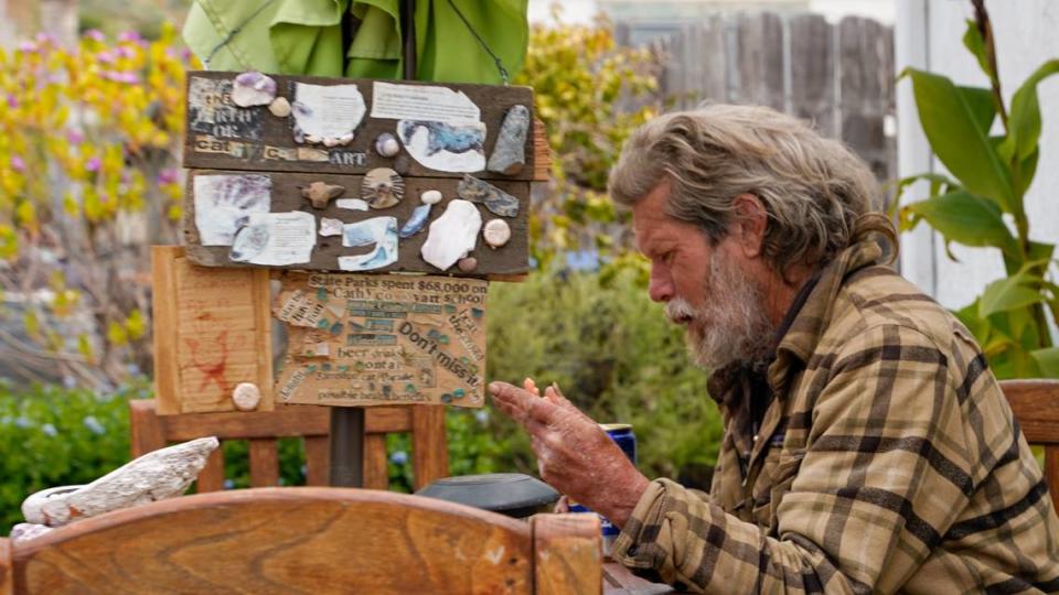 Cowboy, an unhoused resident of Shell Beach, works on a new art project. Cowboy has been homeless for more than 25 years but said he isn’t interested in being housed.