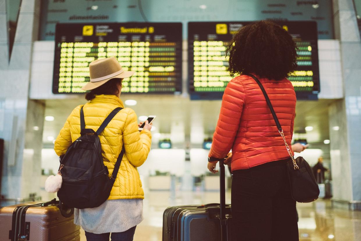 Tourists at the airport waiting for the flight to be announced on the arrival departure board