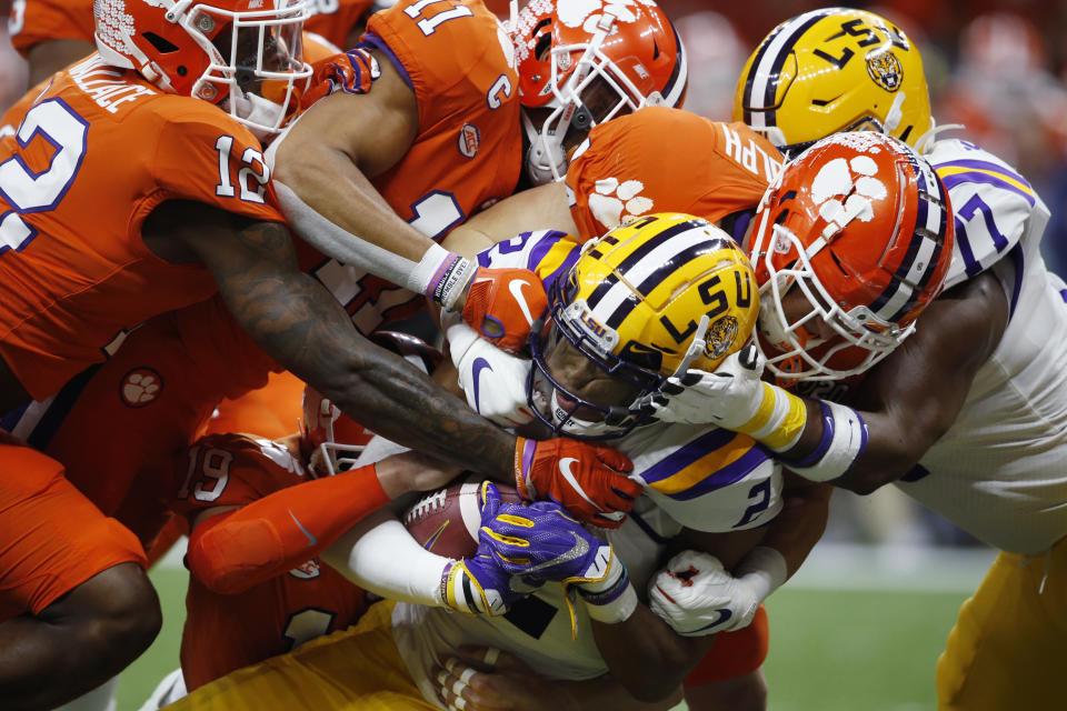 FILE - In this Jan. 13, 2020, file photo, LSU wide receiver Justin Jefferson (2) is tackled by Clemson during the first half of an NCAA College Football Playoff national championship game in New Orleans. The NCAA's latest guidance for playing college sports during the COVID-19 pandemic recommends testing players once a week within 72 hours of competition. For typical Saturday football games, that means Wednesday would be the soonest athletes would be tested. Is that enough for a team of about 100 athletes playing a contact sport to get through a season without major disruptions? Especially, considering simply being exposed to someone who tests positive can land an athlete in quarantine for two weeks? (AP Photo/Gerald Herbert, File)