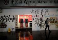 A man walks past a vandalized Bank of China's ATMs after an anti-government protest in Hong Kong