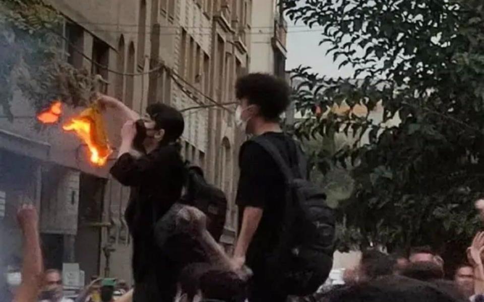 Nika Shakarami burning a hijab in front of a crowd