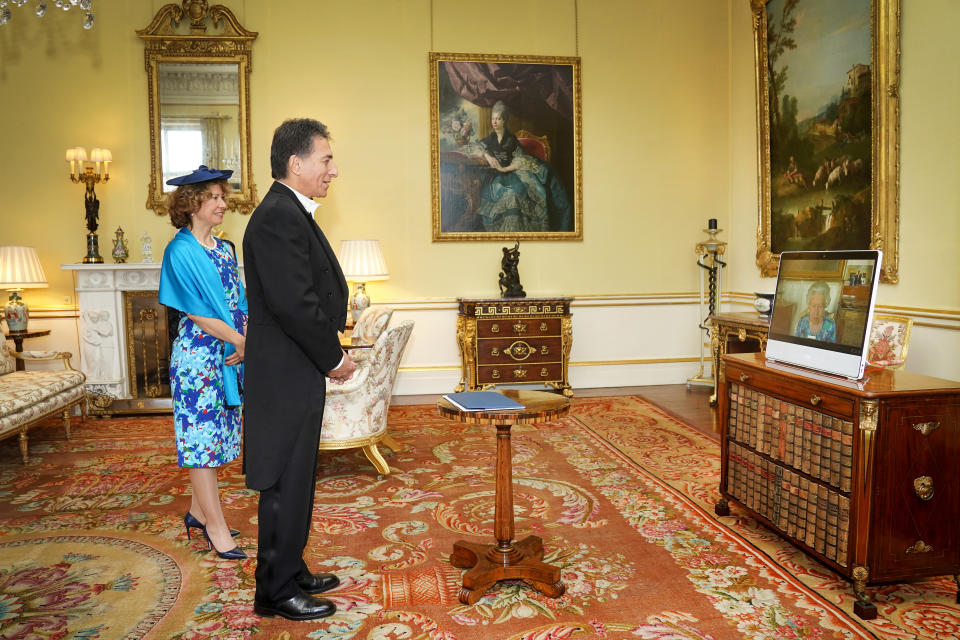 <p>Queen Elizabeth II appears on a screen via videolink from Windsor Castle, where she is in residence, during a virtual audience to receive the Ambassador of Greece, Ioannis Raptakis (centre), and Georgia Soultanopoulou, at Buckingham Palace, London. Picture date: Wednesday October 6, 2021.</p>
