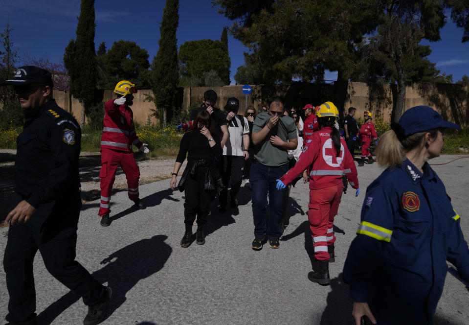 Firefighters and rescuers assist actors posing as fire evacuees during a preparedness drill at Glyka Nera, in northeastern Athens on Thursday, April 4, 2024. Authorities have stepped up exercises ahead of the official start of the fire season on May 1. (AP Photo/Thanassis Stavrakis)