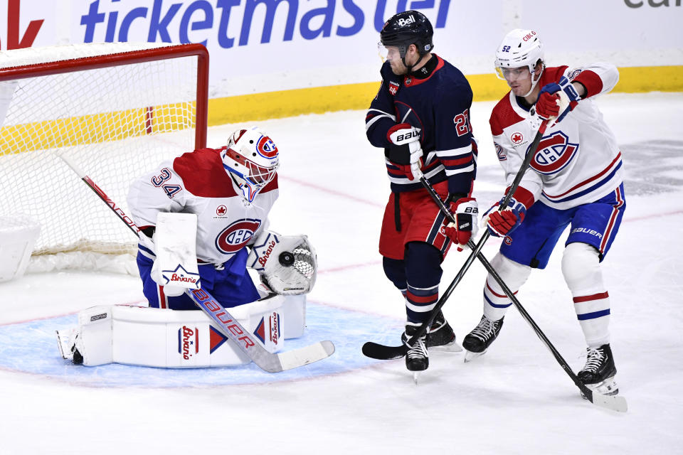 Montreal Canadiens goaltender Jake Allen (34) makes as save as Winnipeg Jets' Nikolaj Ehlers (27) is defended by Canadiens' Justin Barron (52) during the first period of NHL hockey game action in Winnipeg, Manitoba, Monday, Dec. 18, 2023. (Fred Greenslade/The Canadian Press via AP)