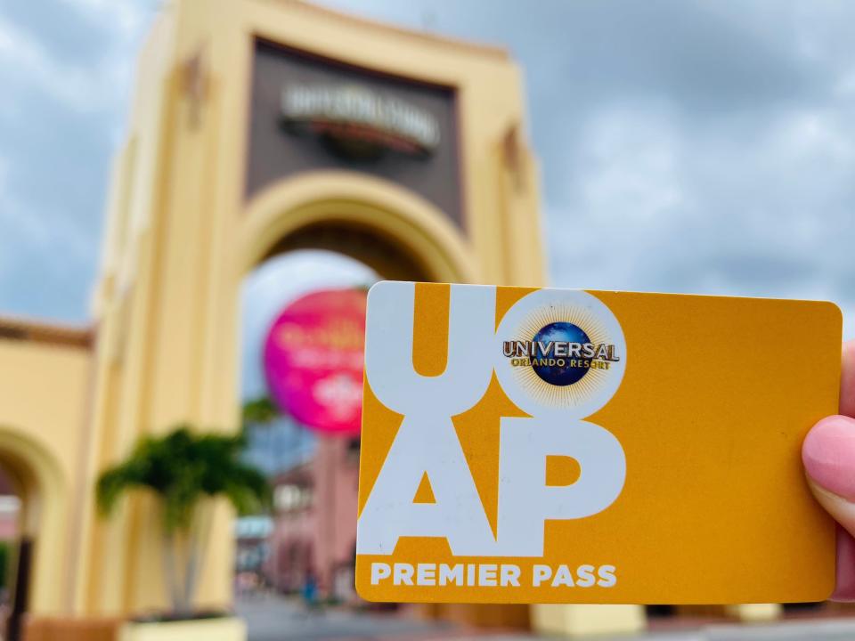 hand holding universal annual pass card in front of theme park entrance