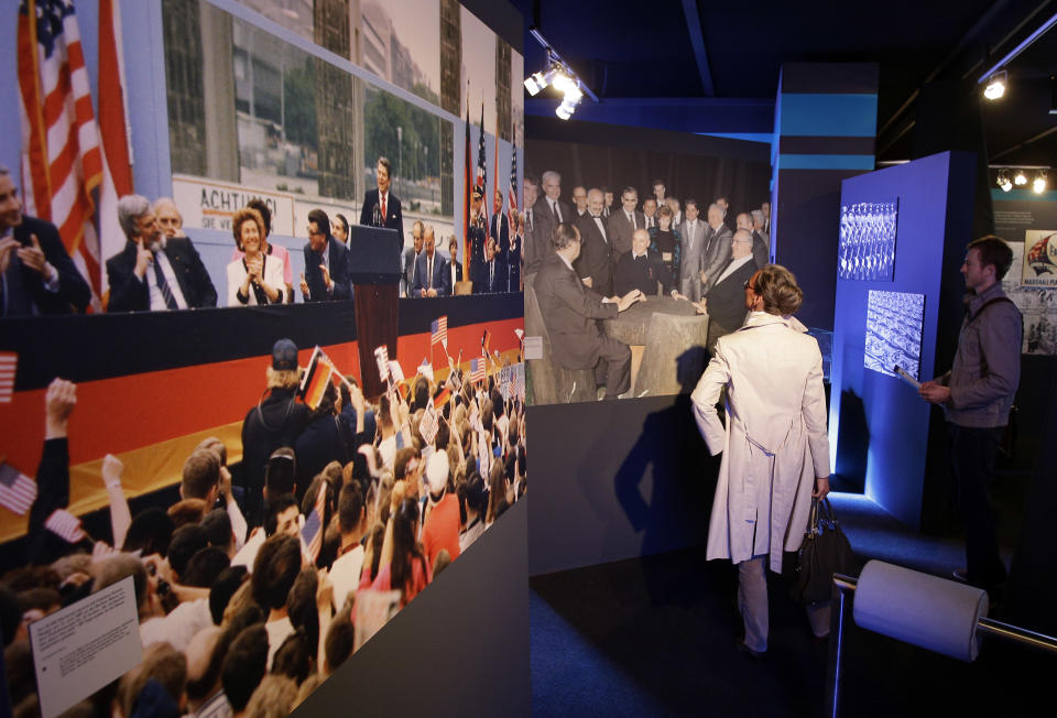 A man and a woman look at photos of US President Ronald Reagan delivering a speech at the Brandenburg Gate and then German Chancellor Helmut Kohl negotiating the German reunification with Soviet leader Michail Gorbachev inside the new cold war museum 'Black Box' at the Checkpoint Charlie in Berlin, Germany, Thursday, Sept. 20, 2012. (AP Photo/Michael Sohn)