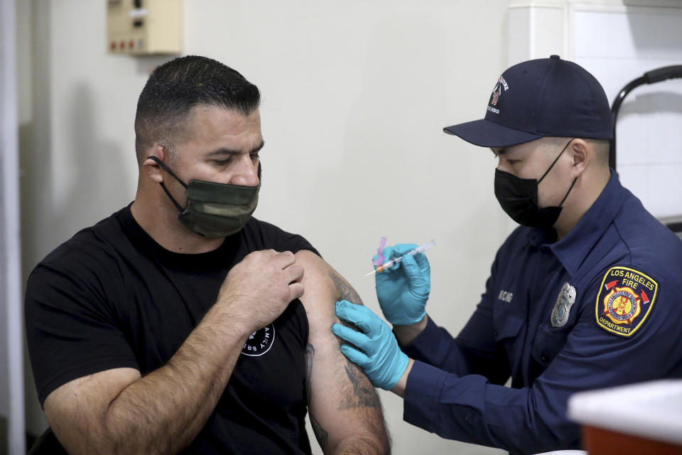 Los Angeles Fire Department Capt. Elliot Ibanez, left, receives the Moderna COVID-19 vaccine given by LAFD paramedic Anthony Kong at Station 4, Monday, Dec. 28, 2020, in Los Angeles. (Gary Coronado/Los Angeles Times via AP, Pool)