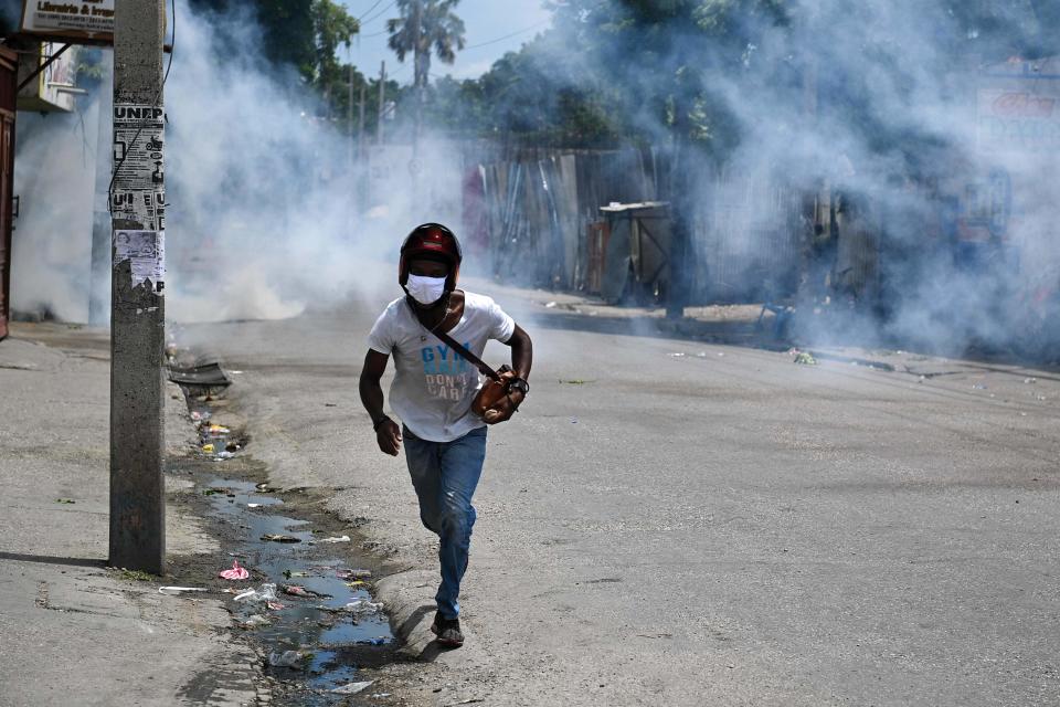 A man runs for cover from tear gas fired by police during a protest against insecurity in Port-au-Prince, Haiti, on August 14, 2023.