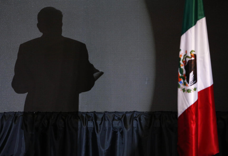 ARCHIVO - La sombra del candidato presidencial Andrés Manuel López Obrador se proyecta en una pantalla mientras da su primer discurso de victoria en la sede de su campaña en el hotel Hilton en Ciudad de México, a fines del 1 de julio de 2018. (Foto AP/Marco Ugarte, Archivo)