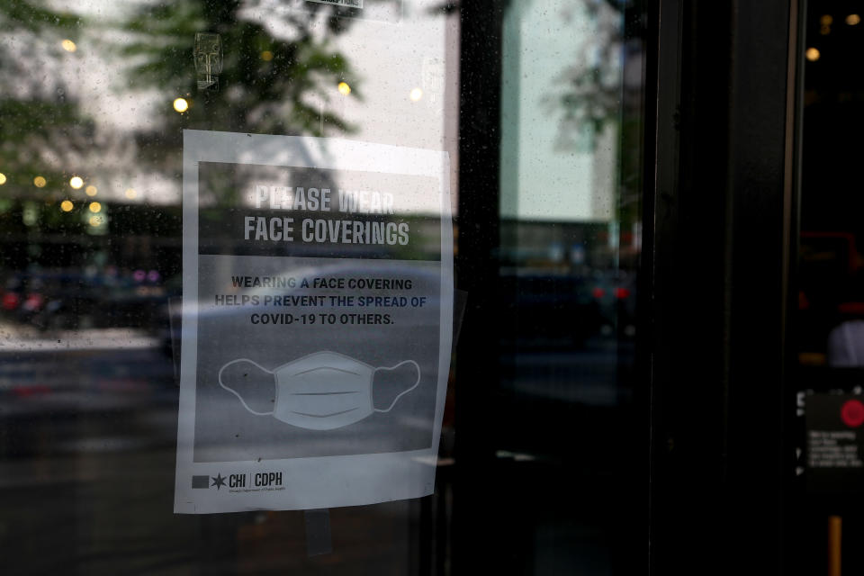 A sign on the door of a shop in Chicago reads, "Please wear face coverings. Wearing a face covering helps prevent the spread of COVID-19 to others."