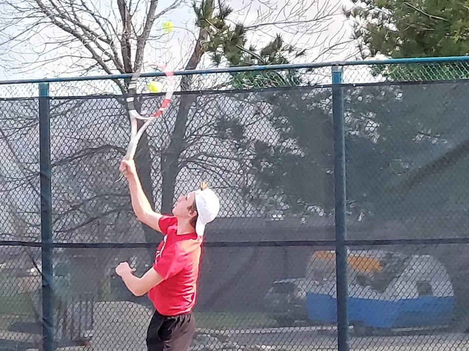 Highland’s Will Lindsco finishes a serve during the No. 1 doubles match on Monday, March 27, at Belleville West High School. The Bulldogs ultimately defeated the Maroons 8-1 in a nonconference match.