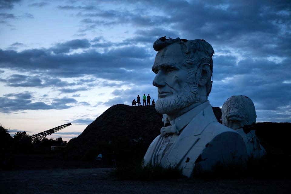 Busts of former US Presidents Abraham Lincoln and George Washington can be seen as people get an overview from a mountain of mulch while they tour the decaying remains of salvaged busts of former US Presidents August 25, 2019, in Williamsburg, Virginia. (Photo: Brendan Smialowski/AFP/Getty Images)