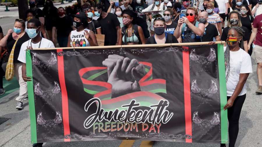 In this June 19, 2020, file photo, demonstrators march through downtown Orlando, Fla., during a Juneteenth event. (Photo by John Raoux, AP, File)