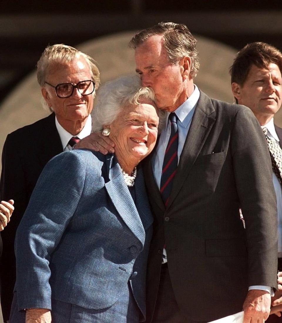 COLLEGE STATION, UNITED STATES:  Former US president George Bush (R) kisses his wife Barbara 06 November as preacher Billy Graham (L) looks on at the conclusion of the dedication ceremony of the George Bush Library in College Station, TX. The current and former presidents of the US and a host of former world leaders and policy makers attended the 06 November dedication of the library. (ELECTRONIC IMAGE)   AFP PHOTO  Joyce NALTCHAYAN (Photo credit should read JOYCE NALTCHAYAN/AFP/Getty Images)