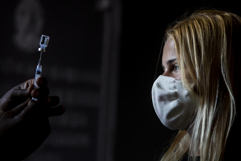 A healthcare worker shows Maria Rosa Machado her dose of the Pfizer COVID-19 vaccine before she is inoculated, on the first day of a vaccination campaign for 17-year-olds, at a vaccination center in Rio de Janeiro, Brazil, Thursday, Aug. 26, 2021. (AP Photo/Bruna Prado)