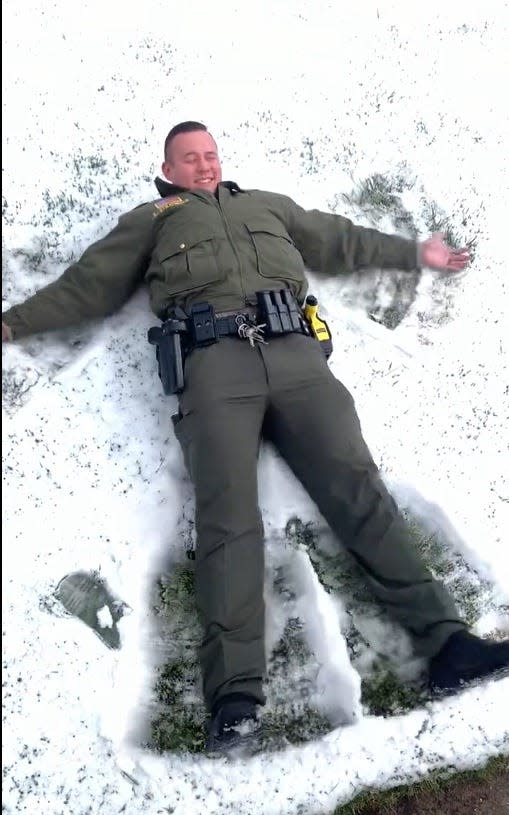 A San Bernardino County Sheriff's deputy in the local mountains creates a snow angel on Thursday.