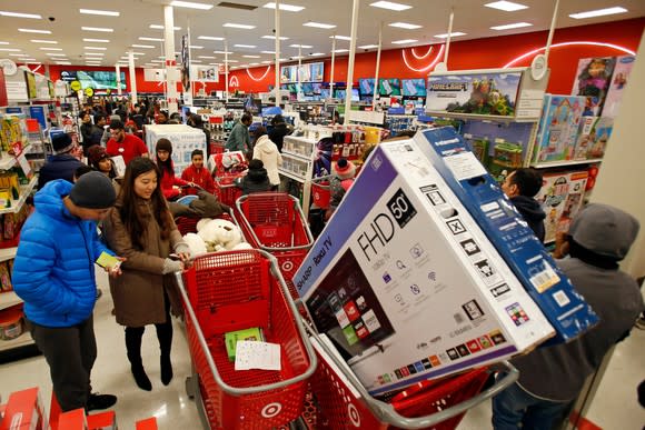 Shoppers line up at Target on Black Friday while once has a shopping cart with a big-screen TV in it.