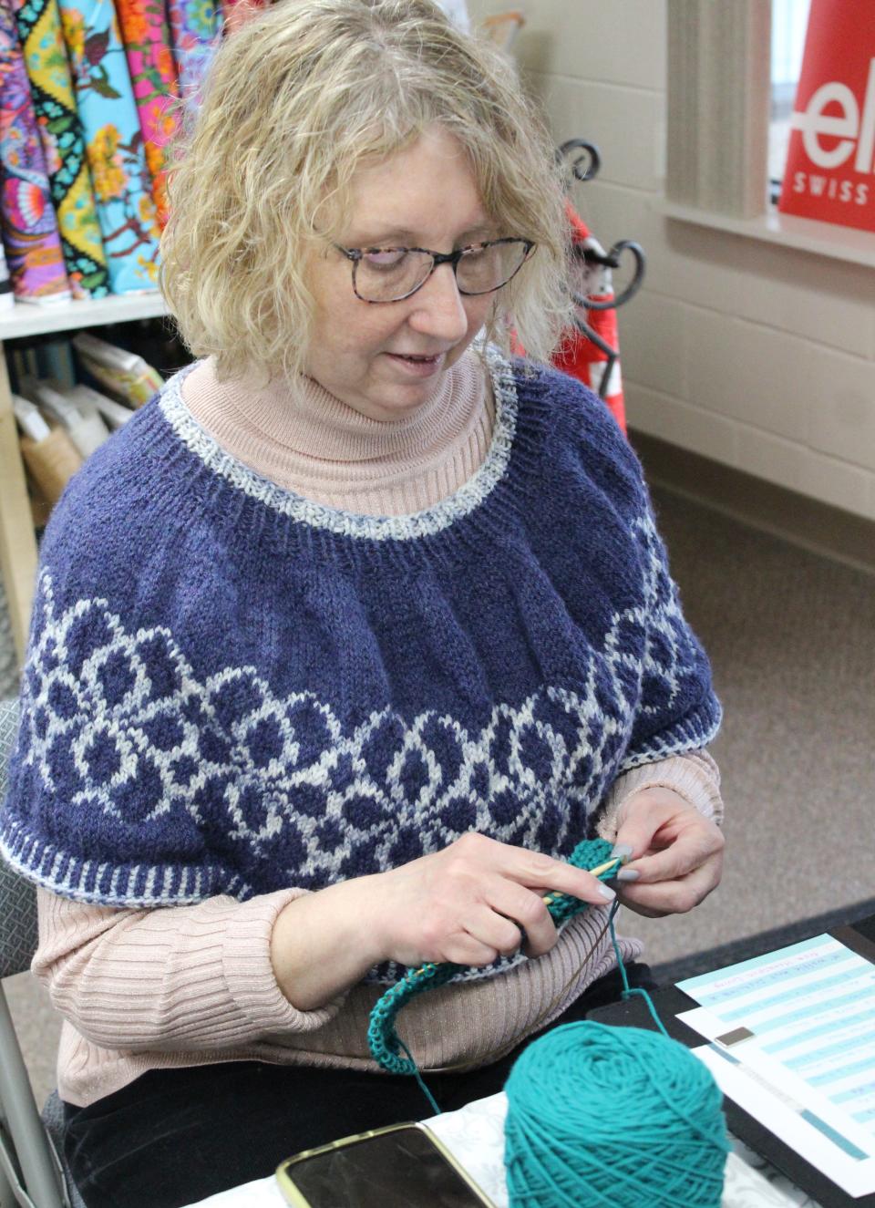 Using teal cotton yarn, Anna Maiden  knits a dishcloth. The Monroe resident knitted the two-tone capelet she is wearing.