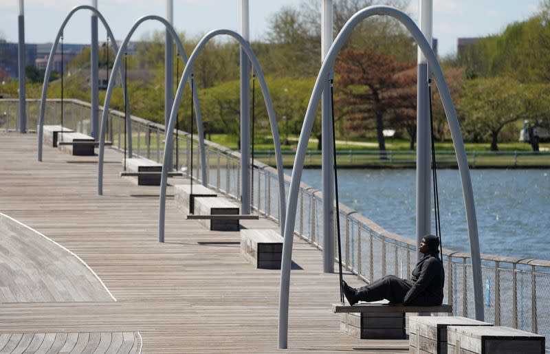 A woman sits alone on a pier at The Wharf in Washington