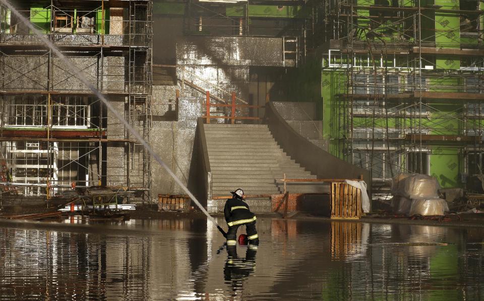 A firefighter sprays water from a hose onto a fire in San Francisco, Tuesday, March 11, 2014. (AP Photo/Jeff Chiu)