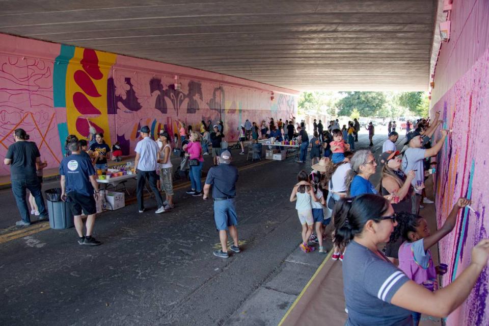 Residents join in to create a mural under Highway 99 as part of the Clean California South Sac Safety & Beautification Project, co-led by Jaya King and Uli Smith, during a public paint day in July 2023. Kevin Neri/Sacramento Bee file