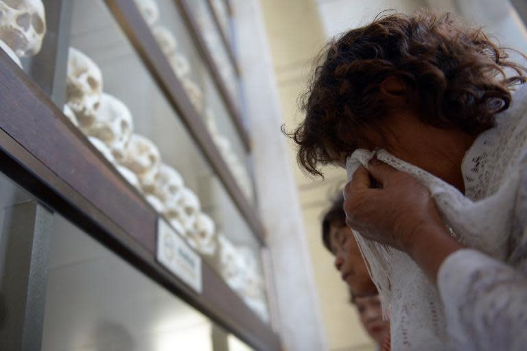 A Cambodian woman cries in front of skulls at Choeung Ek killing fields memorial in Phnom Penh on April 17, 2015