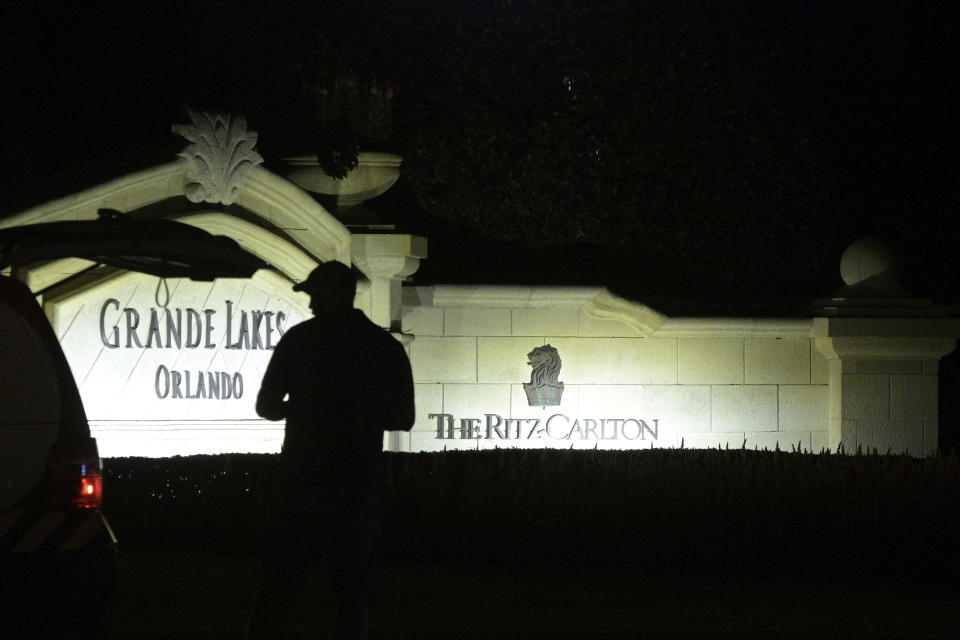 A member of a television news crew works in front of a sign at the resort entrance of The Ritz-Carlton Orlando, Grande Lakes, where actor and comedian Bob Saget was found dead, Sunday, Jan. 9, 2022, in Orlando, Fla. (AP Photo/Phelan M. Ebenhack)