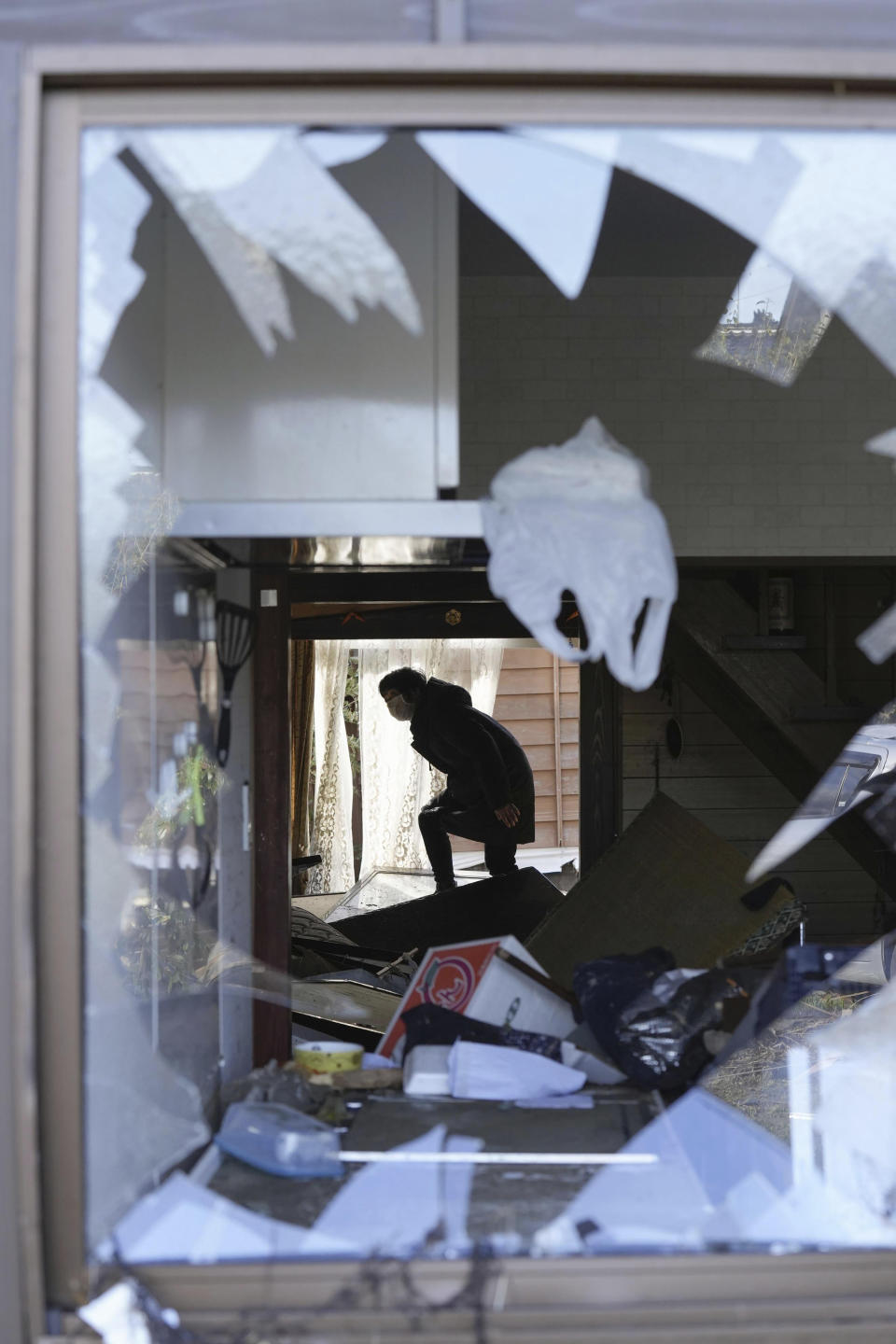 A resident checks her destroyed house in Suzu, Ishikawa prefecture, Japan Friday, Jan. 5, 2024. Monday’s temblor decimated houses, twisted and scarred roads and scattered boats like toys in the waters, and prompted tsunami warnings. (Kyodo News via AP)