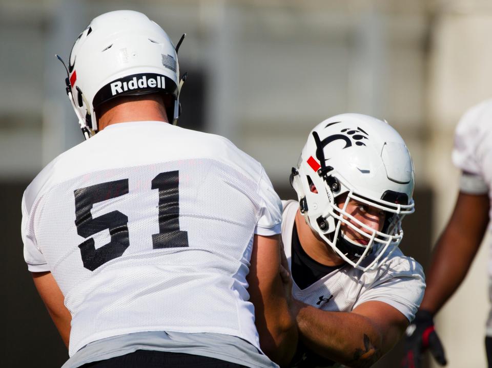 Cincinnati Bearcats offensive lineman Vincent McConnell (77) works by Cincinnati Bearcats offensive lineman Lorenz Metz (51) while working a drill during Cincinnati Bearcats football practice Wednesday, July 31, 2019, at the University of Cincinnati. 