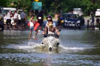 People cross flooded national highway 37 at Kaziranga in Nagaon District of Assam. (Photo credit should read Anuwar Ali Hazarika/Barcroft Media via Getty Images)