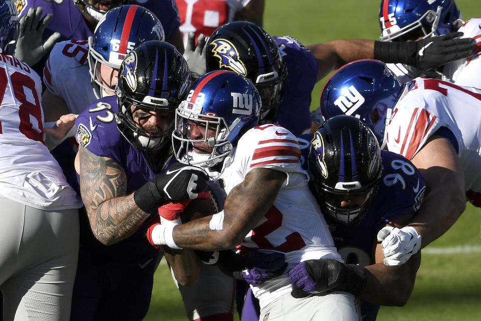 New York Giants running back Wayne Gallman, center, is stopped by Baltimore Ravens defensive end Derek Wolfe (95) and defensive tackle Brandon Williams (98) while running the ball during the first half of an NFL football game, Sunday, Dec. 27, 2020, in Baltimore. (AP Photo/Nick Wass)