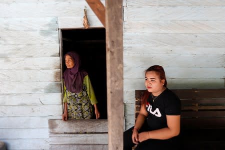 Ipah, 18-year-old woman who is a local resident in Semboja district, sits on a bench as her grandmother looks through a door at her stall near the main road in Kutai Kertanegara regency, East Kalimantan province