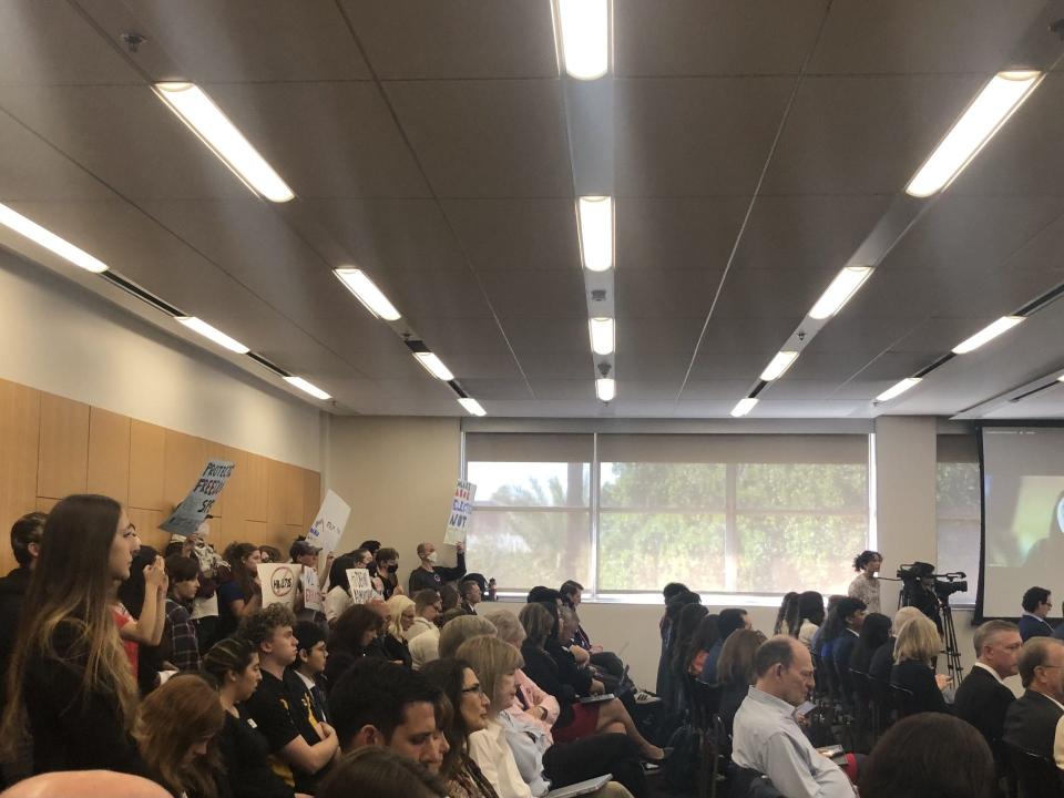 Protesters stand at the back of the room as the Arizona Board of Regents meet on Feb. 22, 2024.