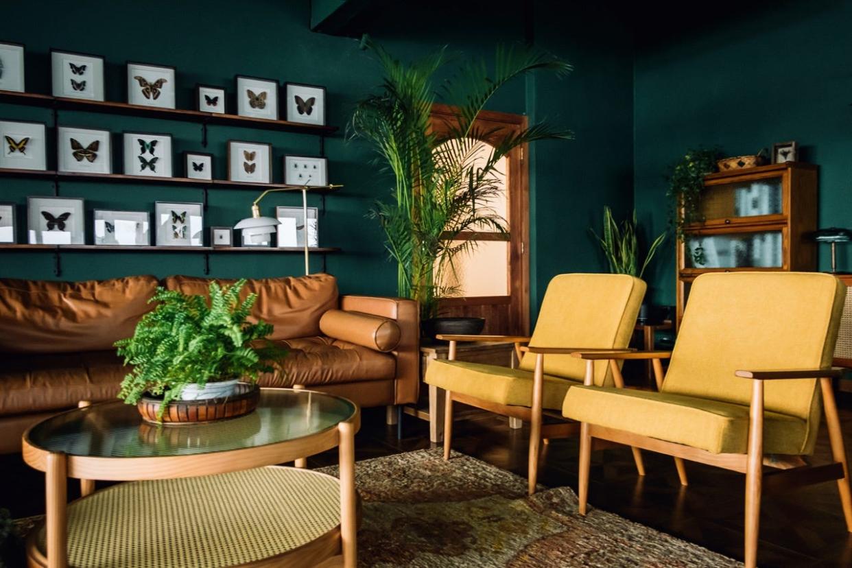 Teal living room with yellow chairs and brown leather couch