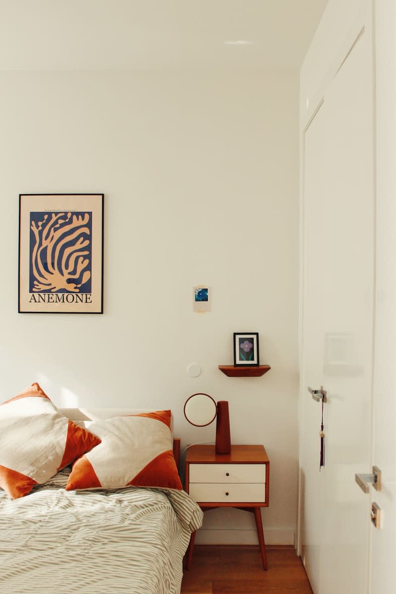 Bedroom with orange and white pillows with wooden nightstand.