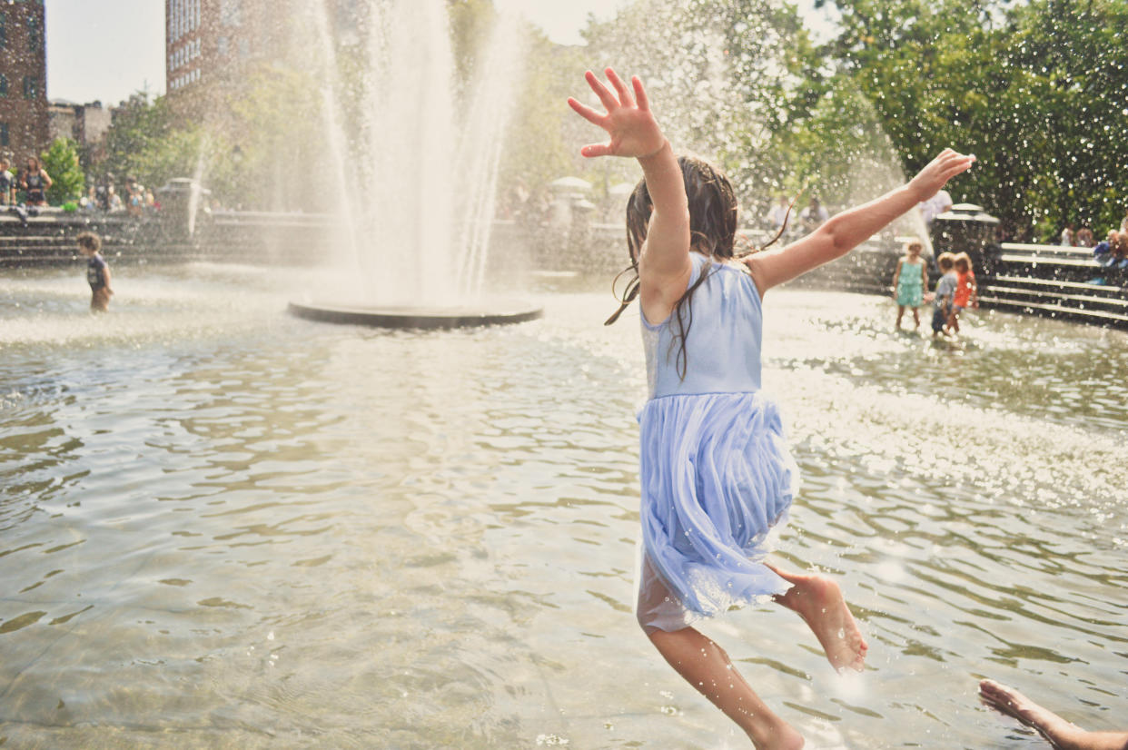 Kleines Mädchen springt in einen Brunnen an einem heißen Sommertag in New york city