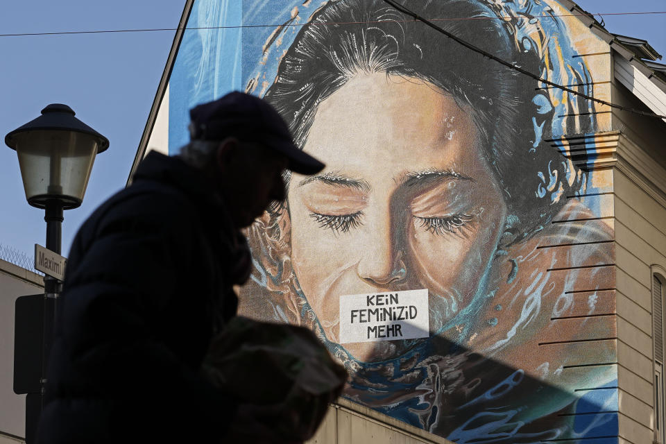 A man passes a large protest painting against hate crime against women, reading "no more femicide" at a house wall in Gelsenkirchen, Germany, on the International Women's Day, Friday, March 8, 2024. Marches, demonstrations and conferences are being held the world over, from Asia to Latin America and elsewhere to mark International Women’s Day. (AP Photo/Martin Meissner)