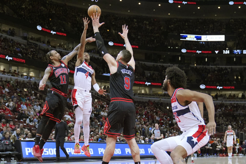 Washington Wizards' Jared Butler tosses up an alley-oop pass to Marvin Bagley III (35) for a dunk as Chicago Bulls' DeMar DeRozan (11) and Nikola Vucevic defend during the first half of an NBA basketball game Monday, March 25, 2024, in Chicago. (AP Photo/Charles Rex Arbogast)