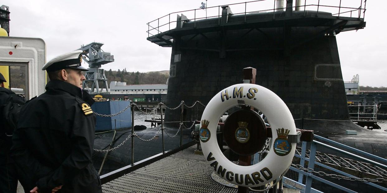 A Royal Navy officer stands in front of submarine HMS Vanguard moored at the Faslane naval base near Glasgow, Scotland December 4, 2006. British Prime Minister Tony Blair committed to keeping a British nuclear arsenal well into the 21st century on Monday, saying the government planned to order new nuclear-armed submarines to replace its existing fleet.