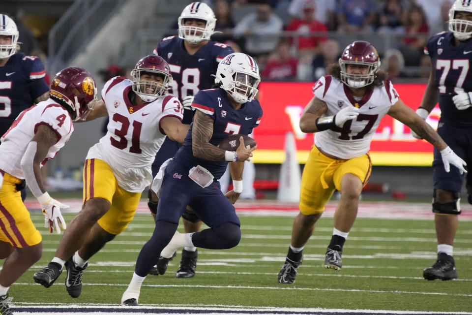 Arizona quarterback Jayden de Laura (7) runs between Southern California defensive back Max Williams (4), defensive lineman Tyrone Taleni (31), and defensive lineman Stanley Ta'ufo'ou (47) in the first half during an NCAA college football game, Saturday, Oct. 29, 2022, in Tucson, Ariz. (AP Photo/Rick Scuteri)