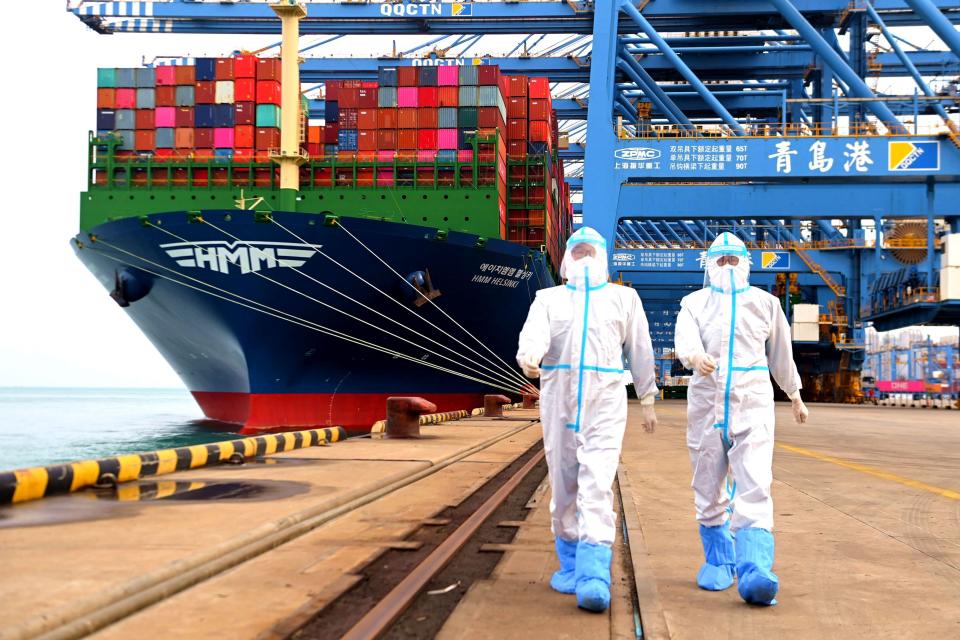 China immigration inspection officers in protective overalls march near a container ship at a port in Qingdao in eastern China's Shandong province Sunday, Nov. 7, 2021. China's exports remained strong in October, a positive sign for an economy trying to weather power shortages and COVID-19 outbreaks.(Chinatopix via AP)