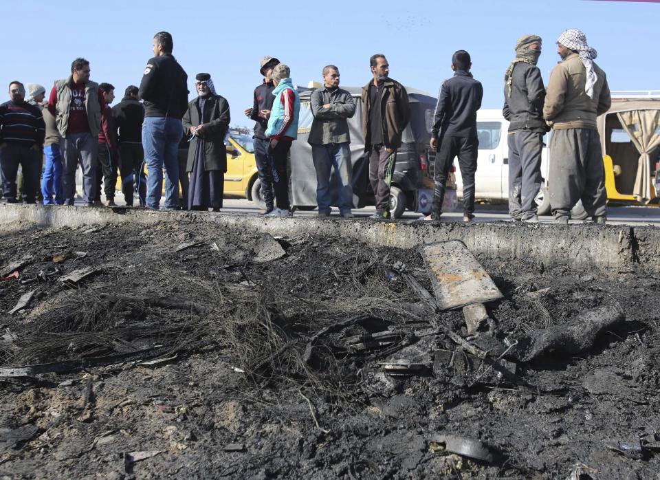 People gather at the scene of a car bombing near an outdoor market in a mostly Shiite neighborhood of Baghdad. Iraq, Thursday, Jan 5, 2017. The car bomb tore through a market on Thursday, killing at least nine people in what appeared to be the latest in a series of deadly attacks by the Islamic State group. (AP Photo/ Karim Kadim)