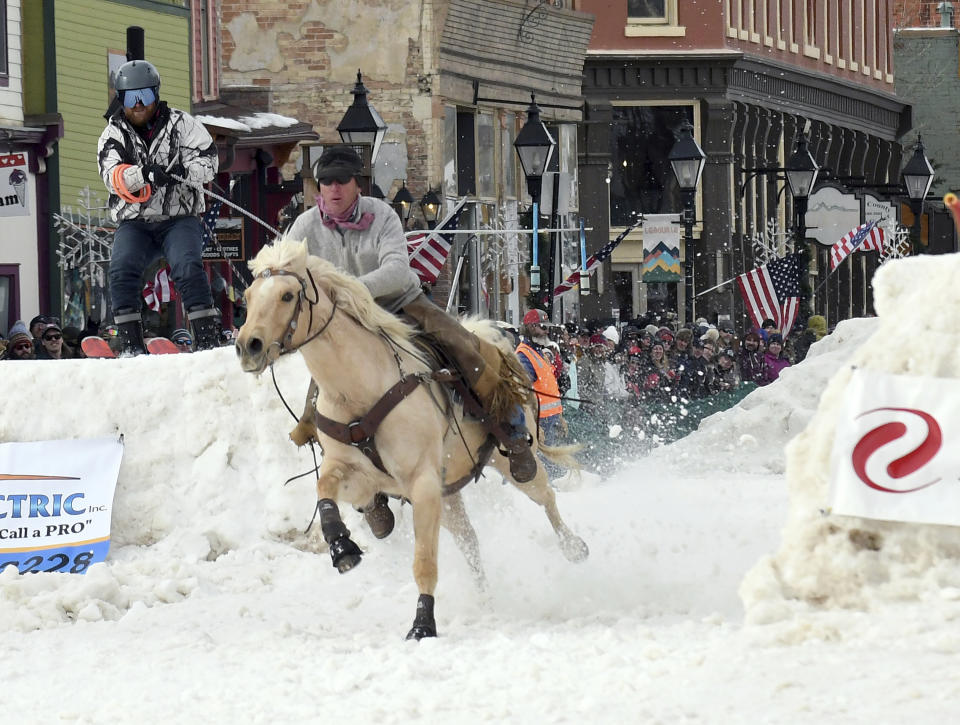 A skijoring team competes in Leadville, Colo., on Saturday, March 2, 2024. Skijoring draws its name from the Norwegian word skikjoring, meaning "ski driving." It started as a practical mode of transportation in Scandinavia and became popular in the Alps around 1900. Today's sport features horses at full gallop towing skiers by rope over jumps and around obstacles as they try to lance suspended hoops with a baton, typically a ski pole that's cut in half. (AP Photo/Thomas Peipert)
