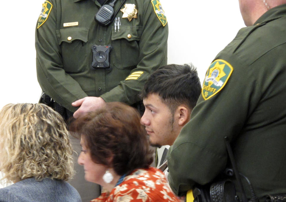 Wilber Ernesto Martinez-Guzman, 19, of El Salvador, listens to proceedings with a public defender and interpreter during his initial appearance in Carson City Justice Court, Thursday, Jan. 24, 2019, in Carson City, Nev. Martinez-Guzman was arraigned on 36 felonies including two dozen weapon charges. He's a suspect in a series of four homicides earlier this month in Reno and south of Carson City in rural Gardnerville. Prosecutors say additional charges are pending. (AP Photo/Scott Sonner).