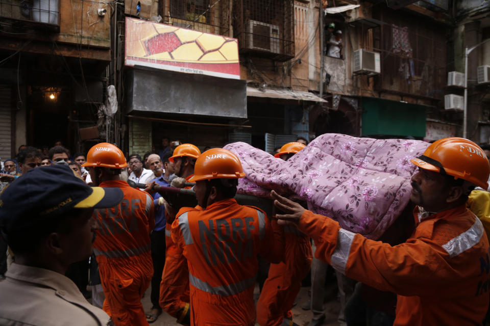 Rescuers carry the body of a victim at the site of a building that collapsed in Mumbai, India, Tuesday, July 16, 2019. A four-story residential building collapsed Tuesday in a crowded neighborhood in Mumbai, India's financial and entertainment capital, and several people were feared trapped in the rubble, an official said. (AP Photo/Rafiq Maqbool)