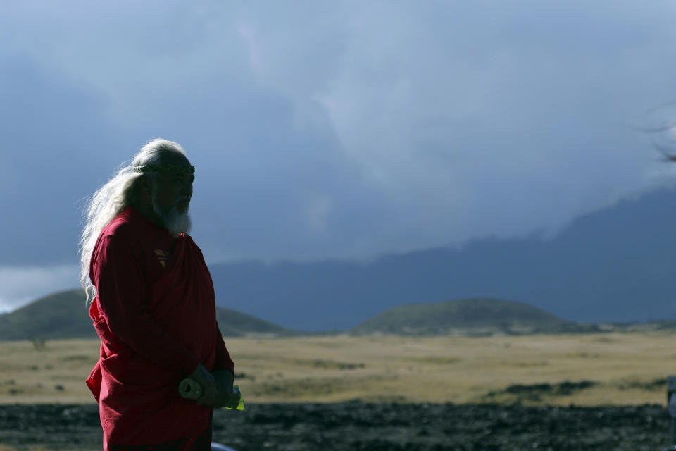 FILE - In this Sunday, July 14, 2019, file photo, a Native Hawaiian activist prays at the base of Hawaii's Mauna Kea. For activists who say they're protecting Mauna Kea, the fight against the proposed Thirty Meter Telescope is a boiling point in Hawaiian history: the overthrow on the Hawaiian kingdom, battles over land, water and development and questions about how the islands should be governed. (AP Photo/Caleb Jones, File)